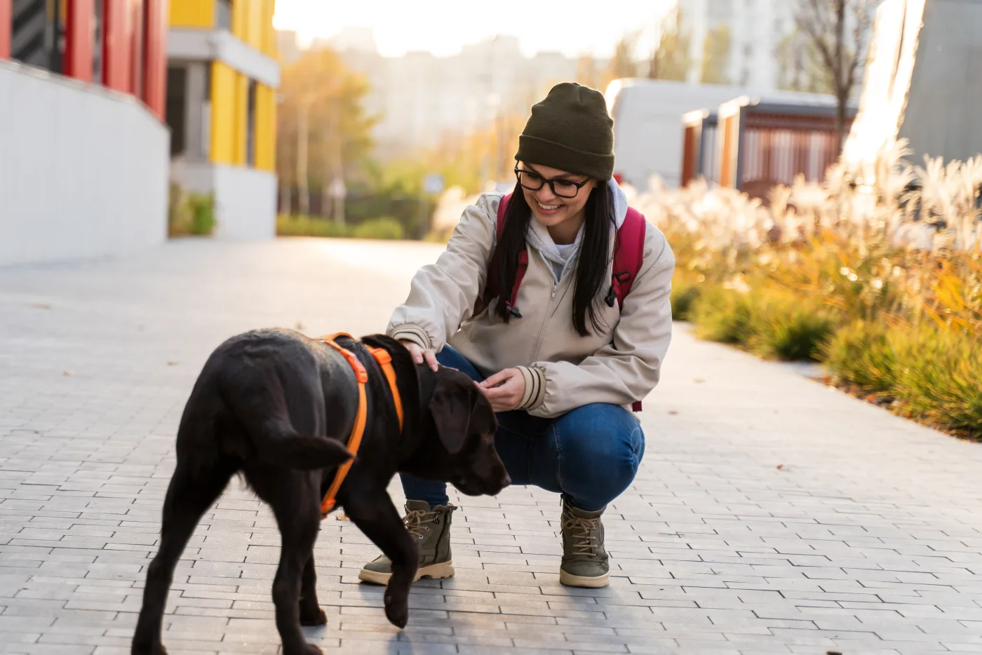 Joven con mochila acariciando a un labrador durante el paseo